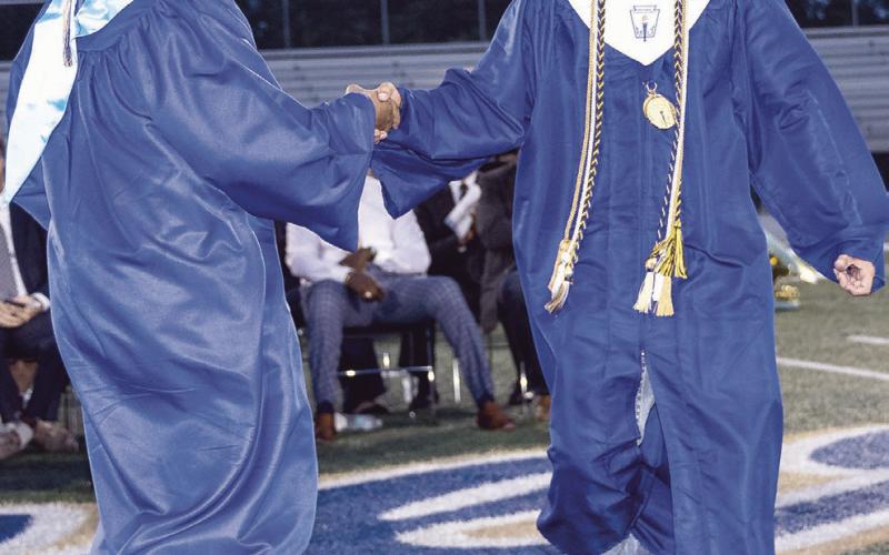 Salutatorian Brody Willard leaves the podium after his address to the crowd and shakes Valedictorian Steven Mora’s hand before he took the podium for his address.