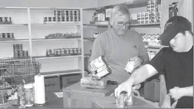 Reporter/Mike Brown Keith Bible (L) and Daniel Brymer sack groceries during Friday distribution at Rock-dale Christian Services Food Pantry.