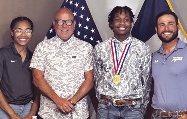 Mayor Ward Roddam read a proclamation honoring Rockdale High School Tiger D’Andre Stephens who scored a gold medal in the UIL Class 3A high jump competition with a 6-foot, 10-inches. They are flanked by DaJoria “DaeDae” Lister and coach Rene Muniz.