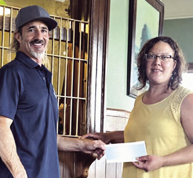 Tommy Neinaber with Sandow Lakes Ranch makes a donation to depot museum manager April Doss.