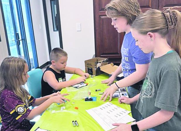 Noah Bradley and Abigail Bradley teaching robotics to Cloverbuds Anna Kroeger and Briggs Berry.