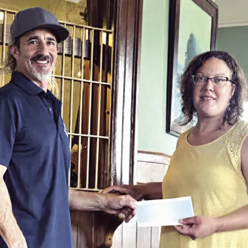 Tommy Neinaber with Sandow Lakes Ranch makes a donation to depot museum manager April Doss.