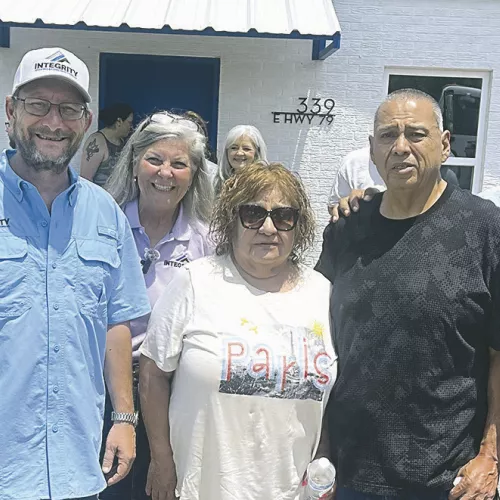 ROOF WINNERS— Rosa and Jesus Garcia were the lucky winners of a brand-new roof from Integrity Roofing at Thursday’s ribbon cutting ceremony, and work on the roof started the very next morning. Shown here (L-R) are Integrity Roofing owners Clint Cox, John Marshall, Debra Jo Cooper, the Garcias, and Vic Salcedo, Territory Sales Manager for Cameron Ashley Building Products who donated the shingles for the project.